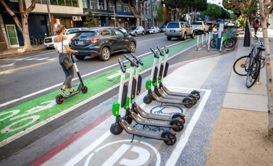 Scooters parked on a street, woman on a scooter